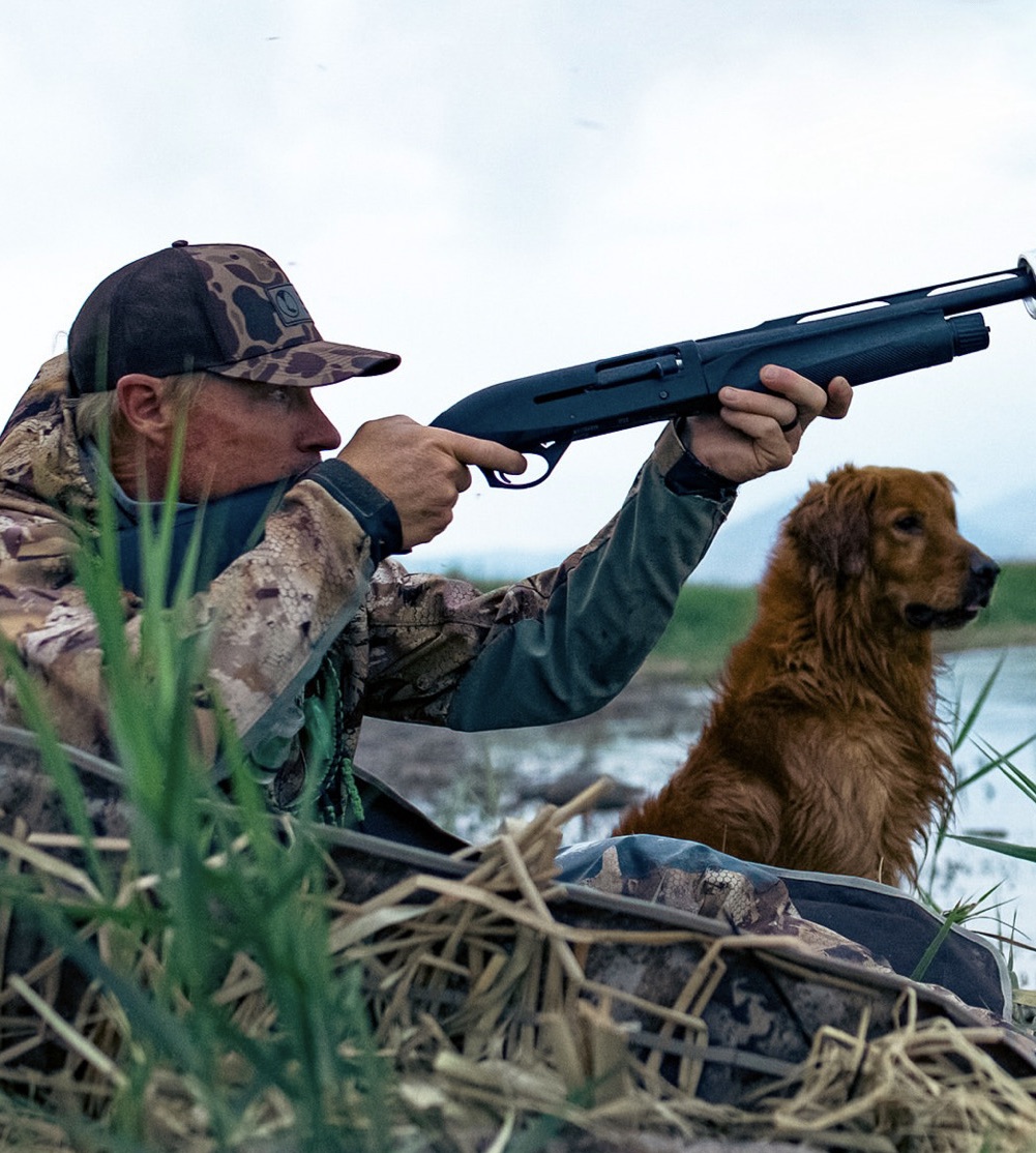 Tyce Erickson with a golden retriever in a hunting blind