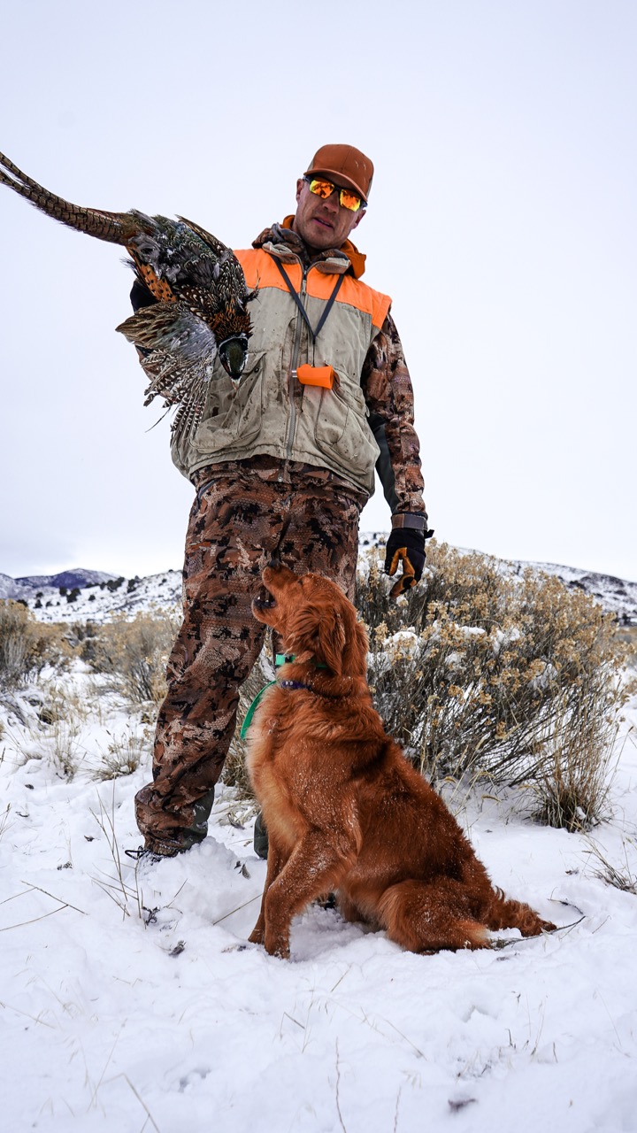 Tyce Erickson with a golden retriever and a pheasant in the snow